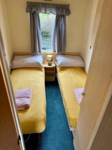 two beds in a small room with a window at Snowdon Bay - North Wales - Stunning Llyn Peninsula Mountain & Ocean Views in Pwllheli