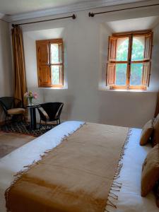 a bedroom with a bed and a table and windows at Maidan El Arsa in Oulad Mazoug