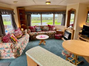een woonkamer met een bank en een tafel bij Snowdon Bay - North Wales - Stunning Llyn Peninsula Mountain & Ocean Views in Pwllheli