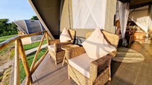 eine Veranda mit Korbstühlen, einem Tisch und einem TV in der Unterkunft Africa Safari Rift Valley 