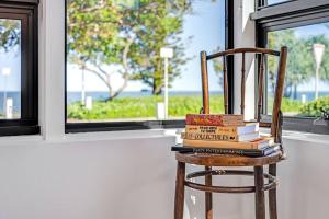 a stack of books on a chair in front of a window at Waterfront Bliss in Margate - 30 min from Brisbane in Redcliffe