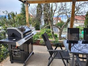 a grill with a tv and a table and chairs at Adriatic SPA Apartment in Selce