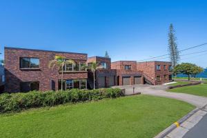 a brick building with a grassy yard in front of it at Waterfront Bliss in Margate - 30 min from Brisbane in Redcliffe
