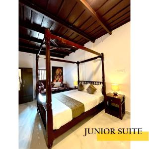 1 dormitorio con 1 cama grande con dosel de madera en UDUPI HERITAGE INN en Udupi