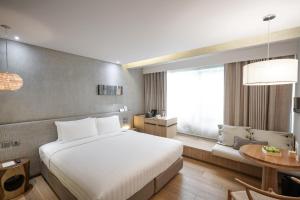 Un dormitorio con una gran cama blanca y una mesa en Ad Lib Hotel Bangkok, en Bangkok