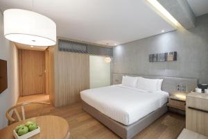 a bedroom with a white bed and a table at Ad Lib Hotel Bangkok in Bangkok