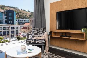 ein Wohnzimmer mit einem TV, einem Sofa und einem Tisch in der Unterkunft Xenia Aparthotel by Totalstay in Kapstadt