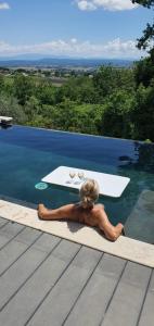 a woman laying on the edge of a swimming pool at La romarine in Bourg-Saint-Andéol