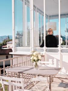 una mujer sentada en un balcón mirando por la ventana en Venegoni Maison De Charme, en Ghiffa