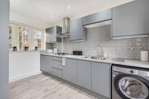 uma cozinha com uma máquina de lavar roupa e uma máquina de lavar roupa em Pass the Keys Superb 3 bed Close to Airport em Wythenshawe