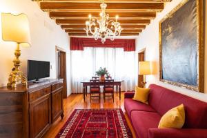 un soggiorno con divano rosso e tavolo di Palazzo Schiavoni Residenza d'Epoca & Suite-Apartments a Venezia