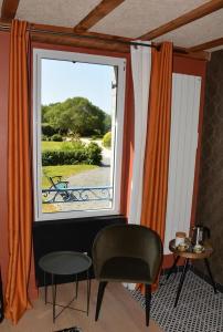 a room with a window and a chair and a table at Le clos de la lande vallée in Bringal