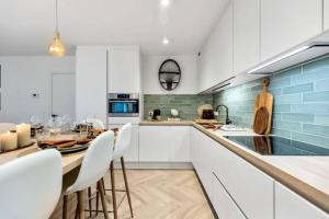 une cuisine avec des placards blancs et une table avec des chaises blanches dans l'établissement Albane - modern 2 slaapkamer appartement, à Ostende