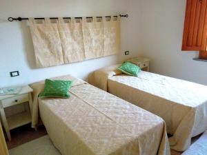 a room with two beds with green pillows at Casa del Cervo in Ingurtosu