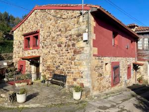 a stone building with a bench in front of it at Casa en aldea frente a la Sierra de el Sueve in Colunga