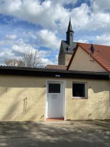 a building with a white door and a church at Ferienwohnung Kornkäfer 2 in Mochau