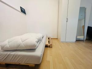 1 cama con sábanas blancas en una habitación con suelo de madera en Wohnung im Herzen der Stadt ,Nähe Stadion. en Dortmund