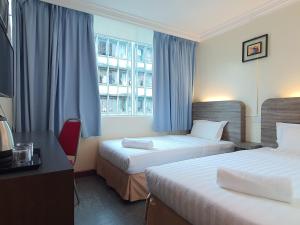 a hotel room with two beds and a window at Capital O 90939 Sandakan Central Hotel in Sandakan