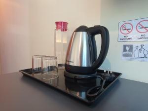 una macchinetta del caffè su un vassoio con due bicchieri di Capital O 90939 Sandakan Central Hotel a Sandakan
