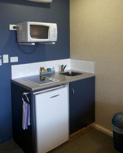 eine kleine Küche mit einer Spüle und einer Mikrowelle in der Unterkunft Landmark Manor in New Plymouth