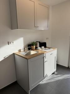 eine Küche mit weißen Schränken und einem Waschbecken in der Unterkunft Edersee Apartment Seeblick 3 in Waldeck