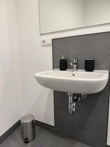 ein weißes Waschbecken in einem Badezimmer mit zwei schwarzen Tassen in der Unterkunft Edersee Apartment Seeblick 3 in Waldeck