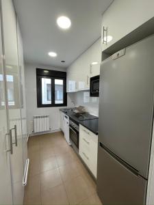 a kitchen with a stainless steel refrigerator and white cabinets at Casa Alberto 2 izda in Tudela +4 photos