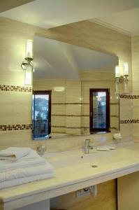 Hotel Bistrita في دوراو: حمام مع حوض ومرآة كبيرة