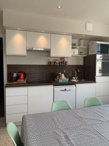 a kitchen with white cabinets and a table and chairs at La Source in Hermanville-sur-Mer