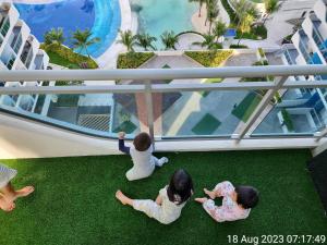 3 niños sentados en el suelo de un balcón con vistas a la piscina en 1BR Unit with Spectacular View Monaco Tower 1430A en Del Rosario
