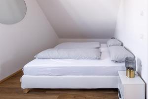 a white bed with white sheets and pillows on it at Ferienwohnung Hendriks in Nonnenhorn