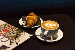 una taza de café y un cruasán sobre una mesa en Quark Hotel Milano en Milán