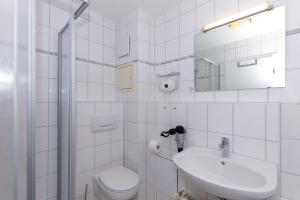 a white bathroom with a toilet and a sink at Strandschloesschen-I-WE-19-682 in Kühlungsborn