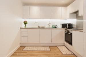 una cocina blanca con armarios blancos y fregadero en Smart & modern Chester city-centre flat - Sleeps 2 en Chester