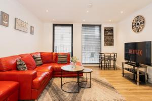 a living room with a red leather couch and a table at Smart & modern Chester city-centre flat - Sleeps 2 in Chester