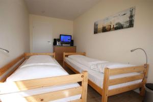 two twin beds in a room with a tv at Strandschloesschen-I-WE-22-685 in Kühlungsborn