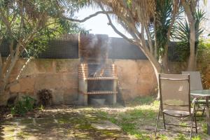 een grill in een tuin met een tafel en een stoel bij Lujosa casa mallorquina restaurada in Ses Salines