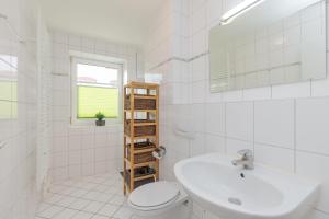 La salle de bains blanche est pourvue d'un lavabo et de toilettes. dans l'établissement Strandschloesschen-I-WE-3-666, à Kühlungsborn
