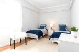 two beds in a white room with blue sheets at Elegant and bright apartment in Estoril in Estoril