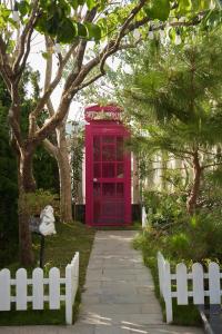 a red phone booth in a garden with a white fence at D HOUSE DALAT 2 in Da Lat