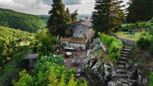 un vieux bâtiment sur une colline avec des arbres dans l'établissement Rifugium, à Greve in Chianti