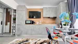 eine Küche mit einem Tisch und einem TV an der Wand in der Unterkunft Cosmopolitan - Studio pe plaja cu vedere la mare & loc parcare gratis in Mamaia Nord – Năvodari