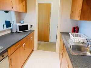 uma cozinha com um lavatório e um micro-ondas em Modern 2 Bed Apartment Close to Gla Airport & M8 em Paisley