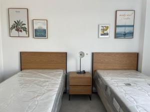 ein Schlafzimmer mit 2 Betten und einem Nachttisch mit Bildern an der Wand in der Unterkunft Costa Ballena - Dos dormitorios, Piscina y Jardín privado in Cádiz + 45 Fotos