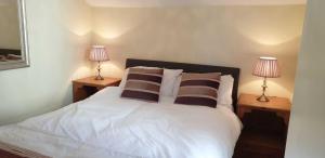 1 dormitorio con 1 cama blanca y 2 lámparas en Upwey, en Weymouth