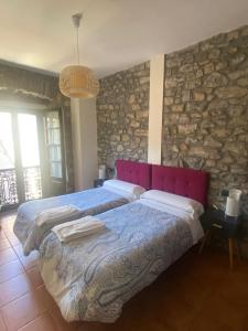 a bedroom with two beds and a stone wall at Apartamentos Hevia in Villaviciosa