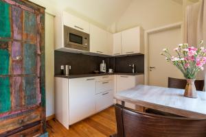 a kitchen with white cabinets and a table with a vase of flowers at Dat Lütthus in Ahrenshoop