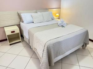 1 dormitorio con 1 cama blanca grande y 2 almohadas blancas en Flat Exclusivo no Crystal Apart Hotel! en Macaé