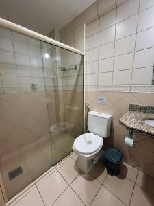 uma casa de banho com um WC e uma cabina de duche em vidro. em Flat Exclusivo no Crystal Apart Hotel! em Macaé