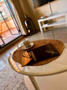une table en verre avec un livre et une tasse sur le dessus dans l'établissement Casa Aurora ~ A Modern, welcoming apartment, à Jávea